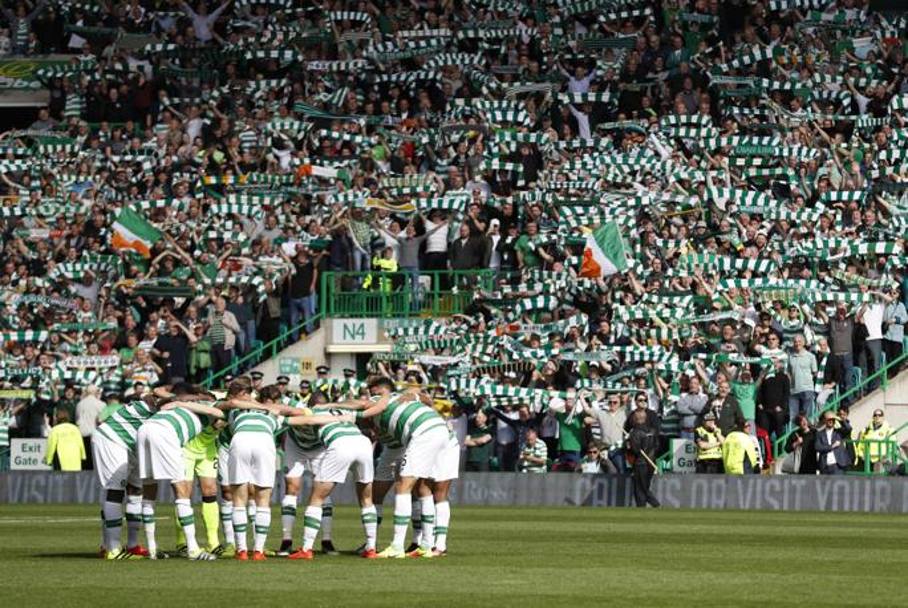 L&#39;abbraccio tra i giocatori del Celtic prima del derby davanti alla curva biancoverde con tifosi in piedi. REUTERS